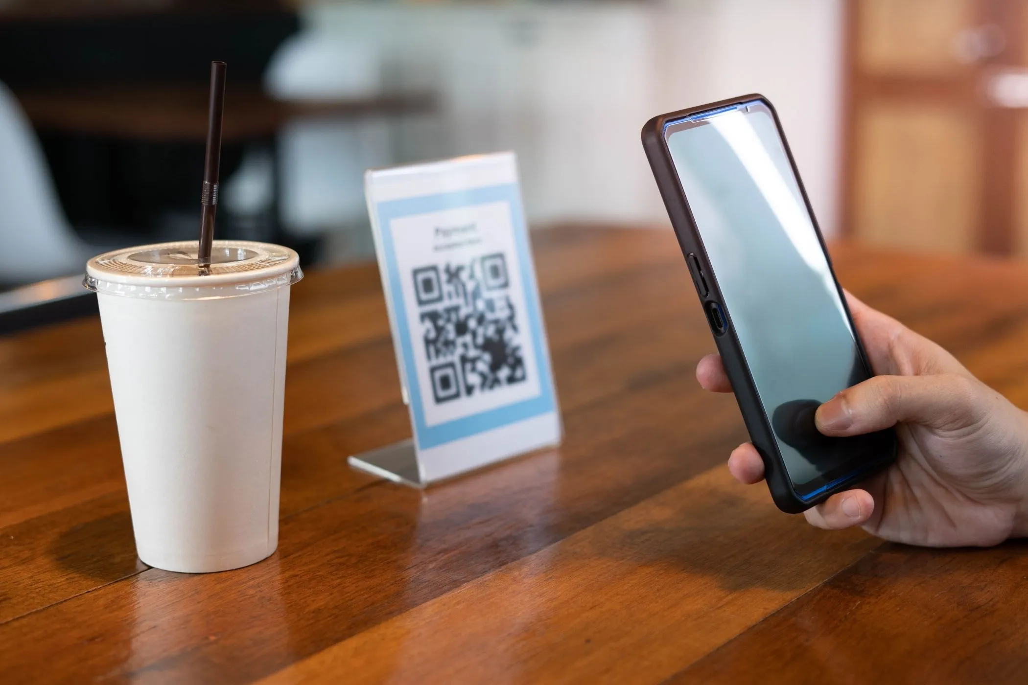 A hand scanning a QR code at a café